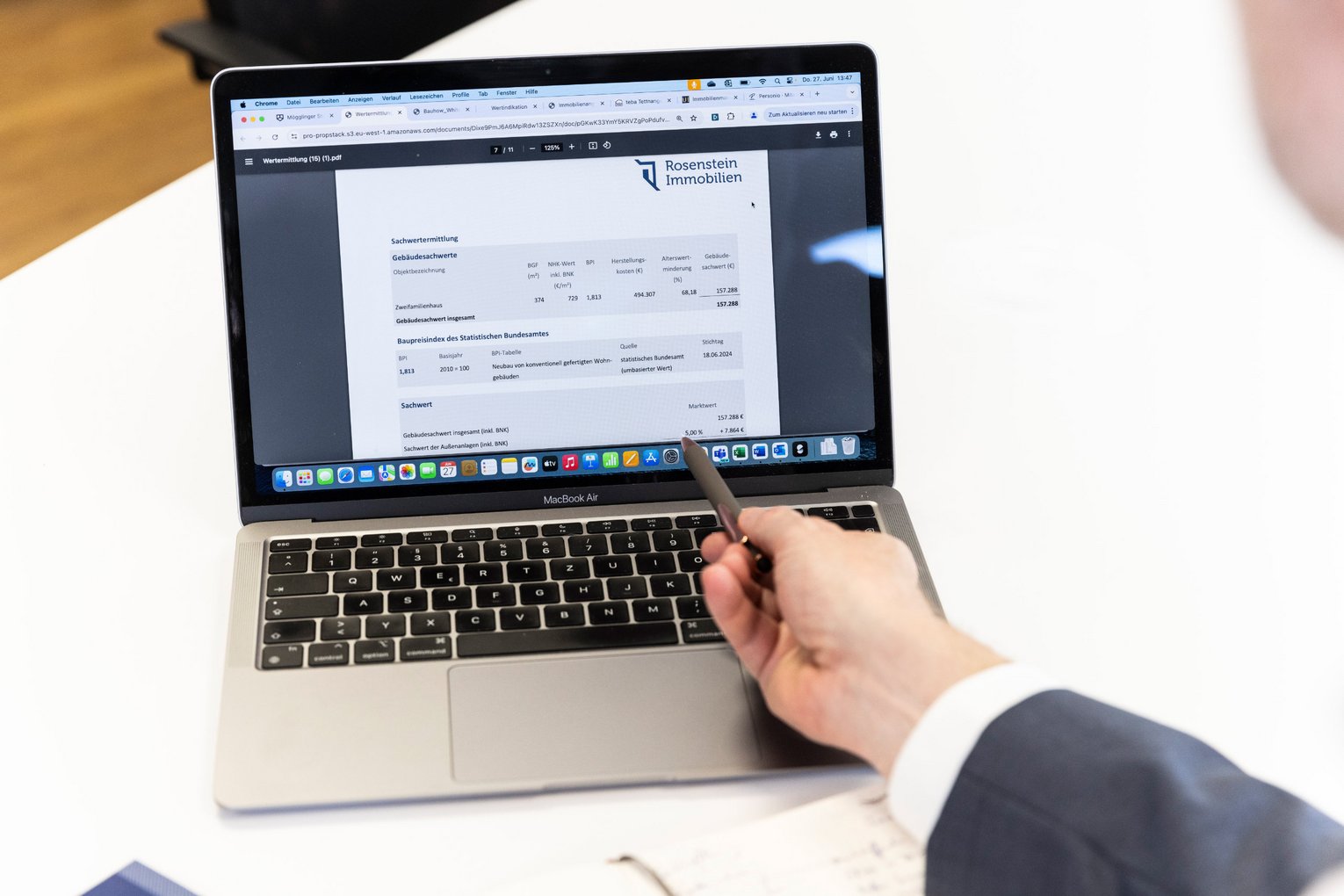 Onlinebewertung Immobilien Makler zeigt auf Bildschirm mit Immobilienbewertung